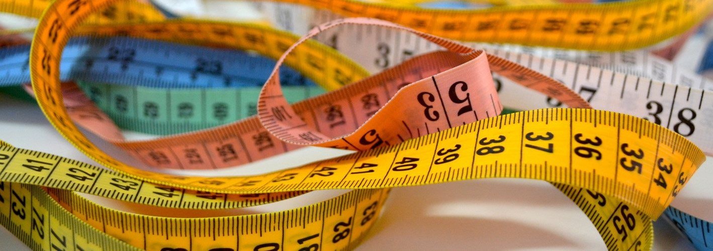 various colorful tape measures laying tangled on a table